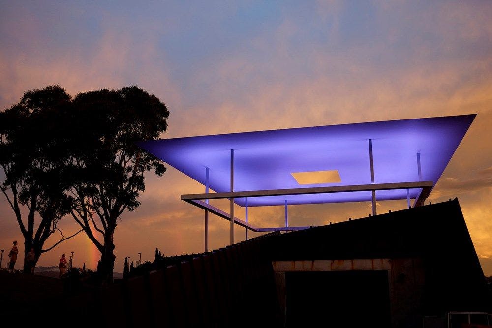 A large outdoor light installation, projecting blue/purple hues at night