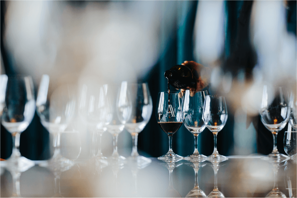 Red wine being poured photographed through layers of wine glasses