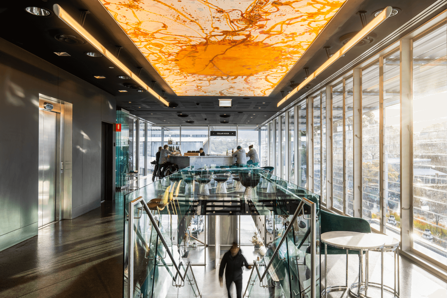 A room with floor to ceiling glass and people undertaking a tasting under Joh Olsen's The Source