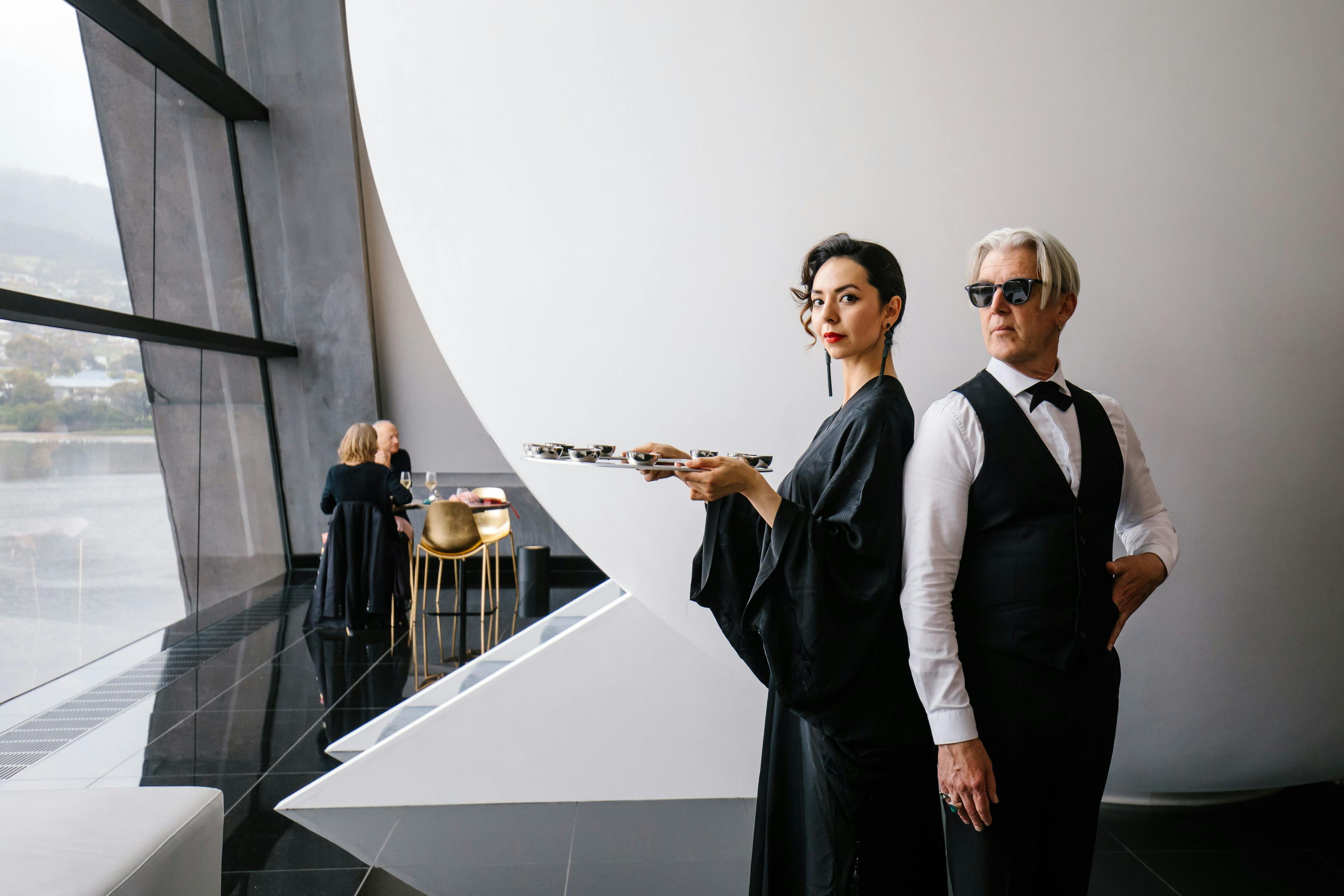 Two elegantly dressed butlers stand posed ready to serve.