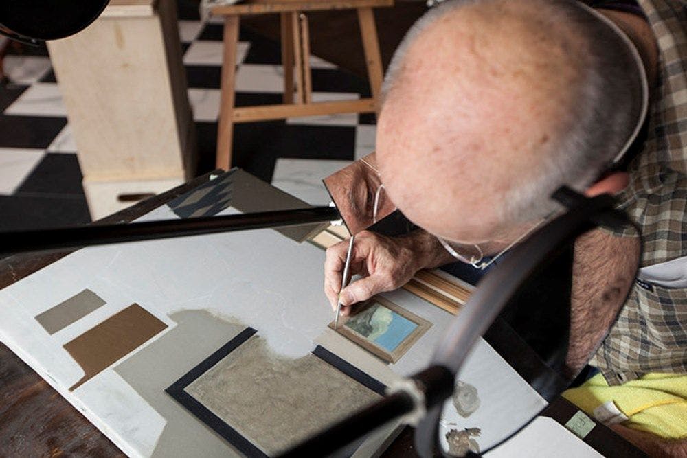 An artist painting over a desk inside the museum.